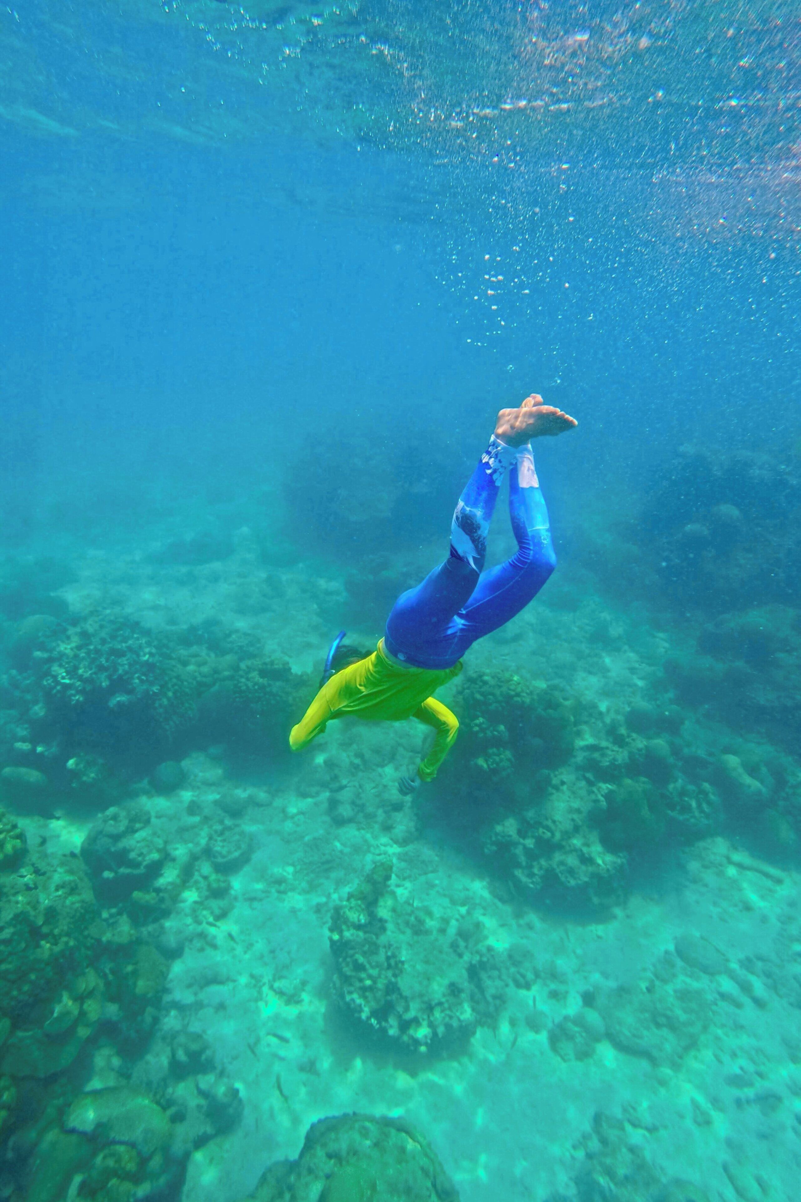 A person underwater, surrounded by a rocky seabed.