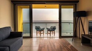 A modern living room with a sofa, two chairs, a floor lamp, and a view of the sea through large glass doors. - Delta Hotels by Marriott Riviera Veracruz (Alvarado)