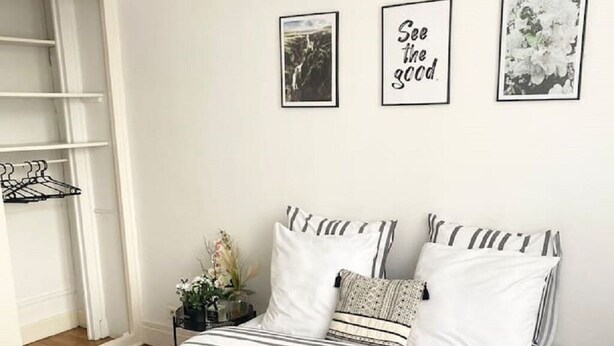 A bedroom with a bed, pillows, a bedside table with a vase, and wall art. - Grand T2 Lumineux Pied du Métro et Centre de Lyon (Villeurbanne)