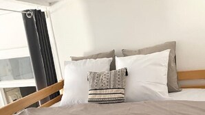 Ett hotellrum med en säng, kuddar och utsikt över omgivningarna.