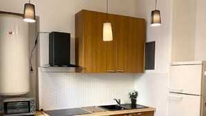 Ett modernt kök med träskåp, en vit bänkskiva och en matplats med gröna tallrikar och glas.