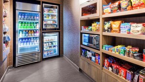 Ein Automatenbereich für Snacks und Getränke mit mehreren Kühlschränken und Regalen, gefüllt mit verschiedenen Speisen und Getränken.