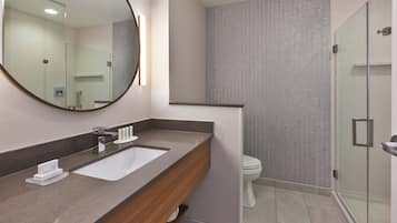 A modern bathroom with a large mirror, a sink, and a shower area.