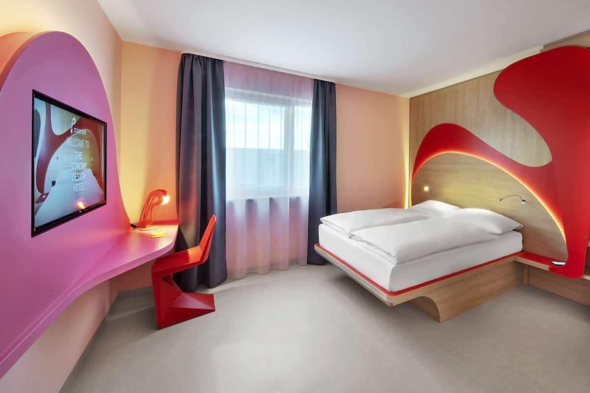 Una habitación de hotel moderna con una cama, un escritorio y una pantalla de televisión mostrando un mensaje de bienvenida.