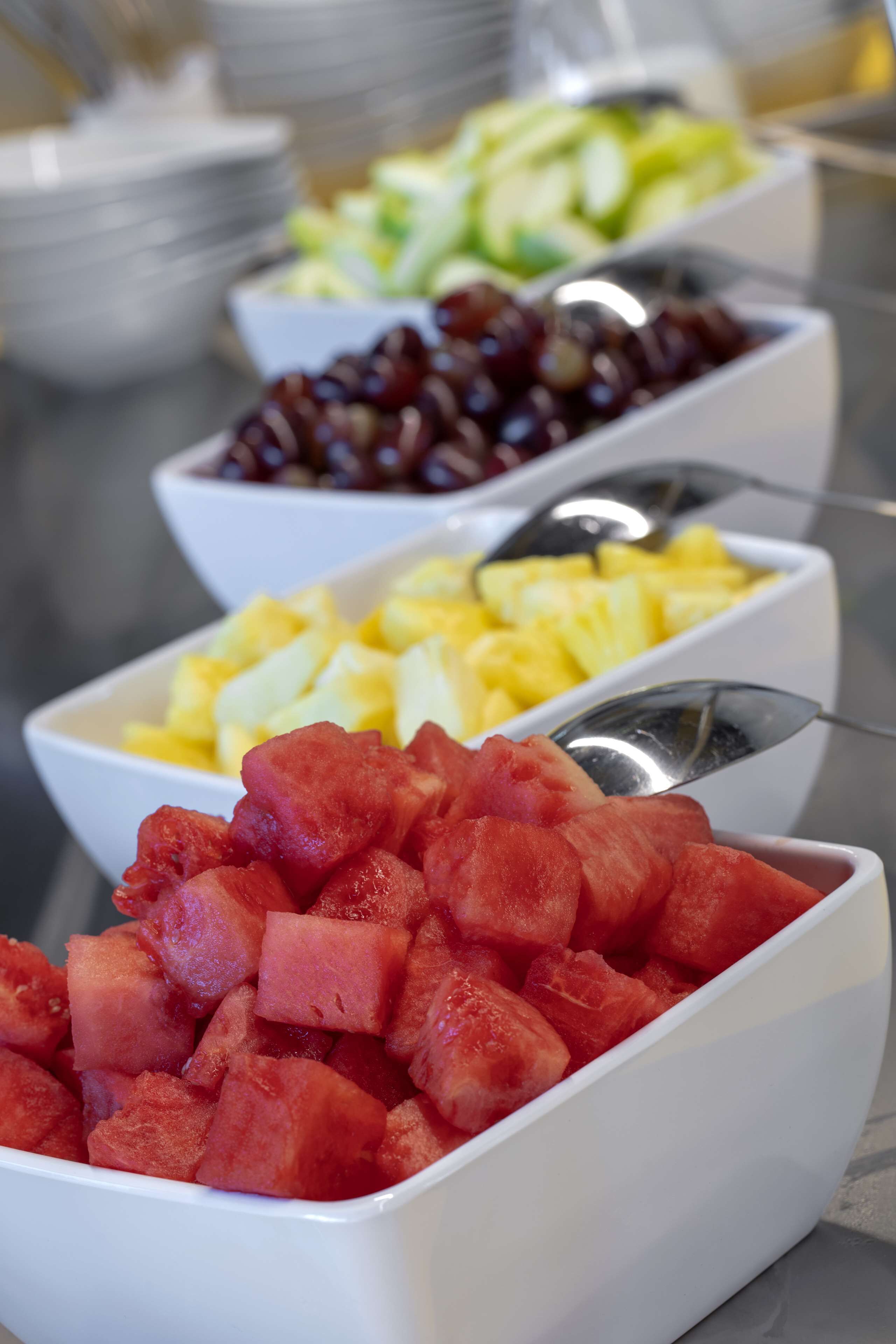 A buffet with various fruits including watermelon, pineapple, grapes, and melon.