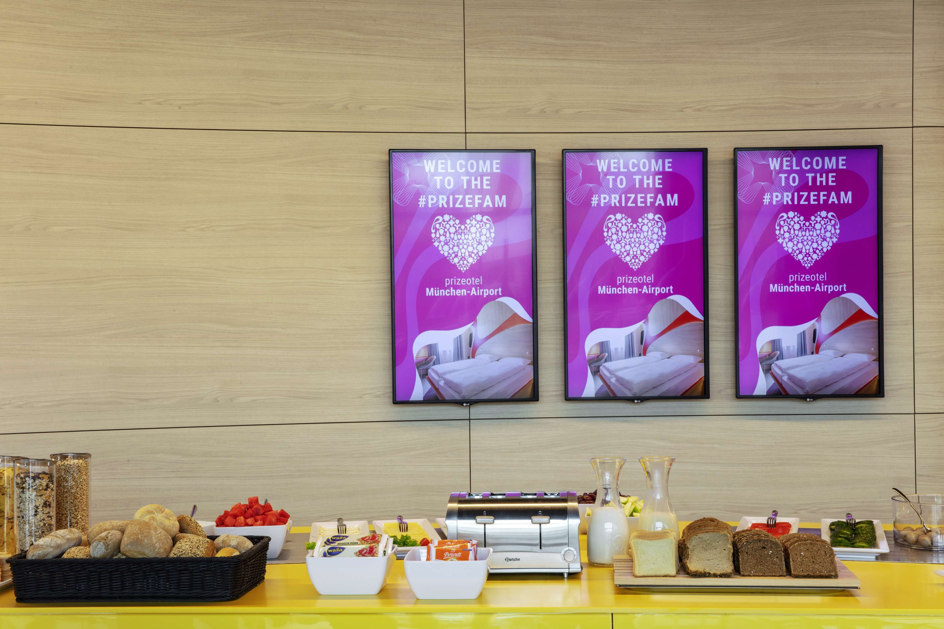 Tres letreros de bienvenida con diseño de corazón, una mesa de buffet con diversas opciones de comida y una botella de leche.