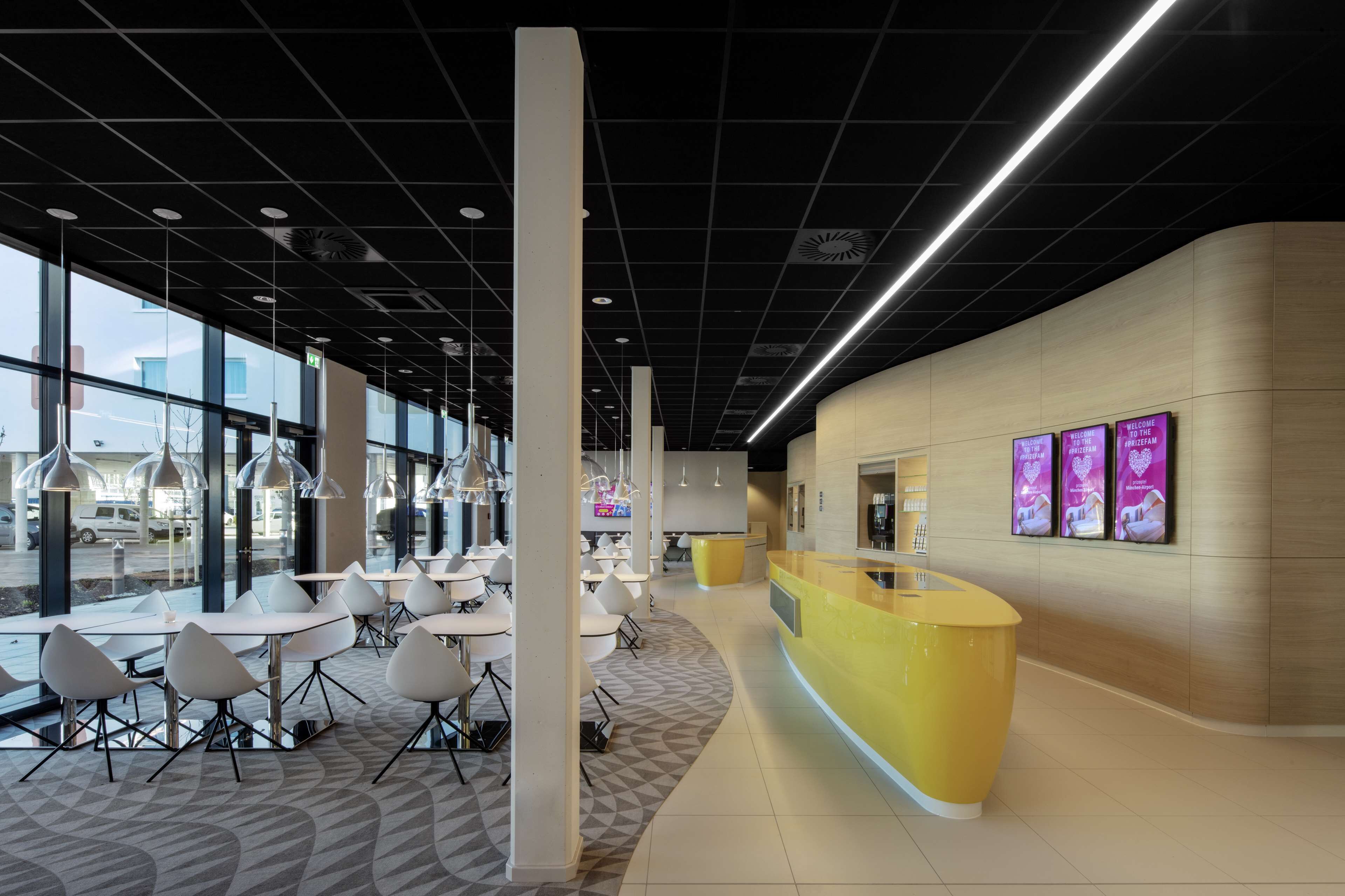 Un interior moderno con mostrador de recepción, zona de estar y grandes ventanales que ofrecen vistas al exterior.