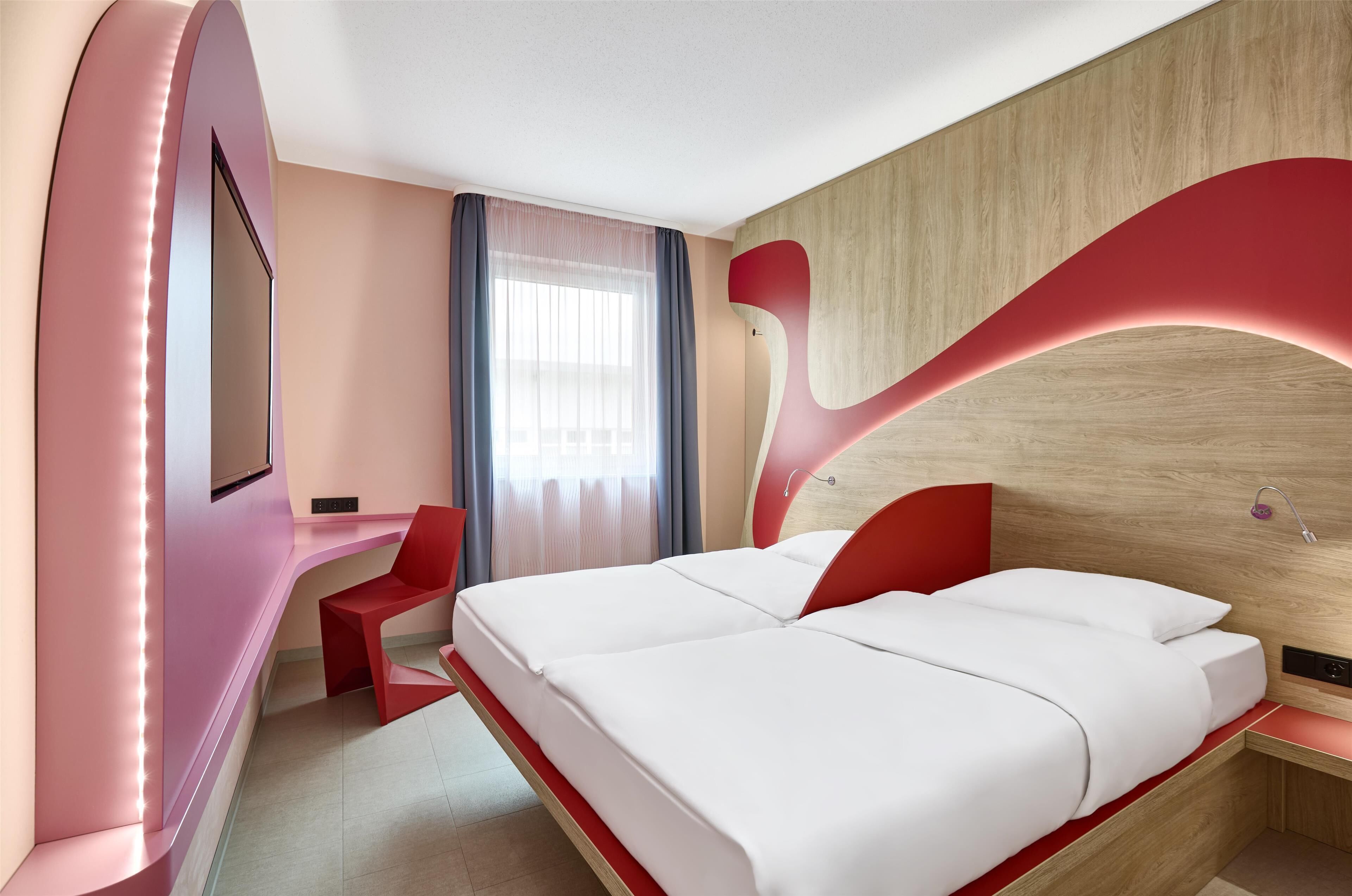 Een moderne hotelkamer met een groot bed, een bureau en een televisie.