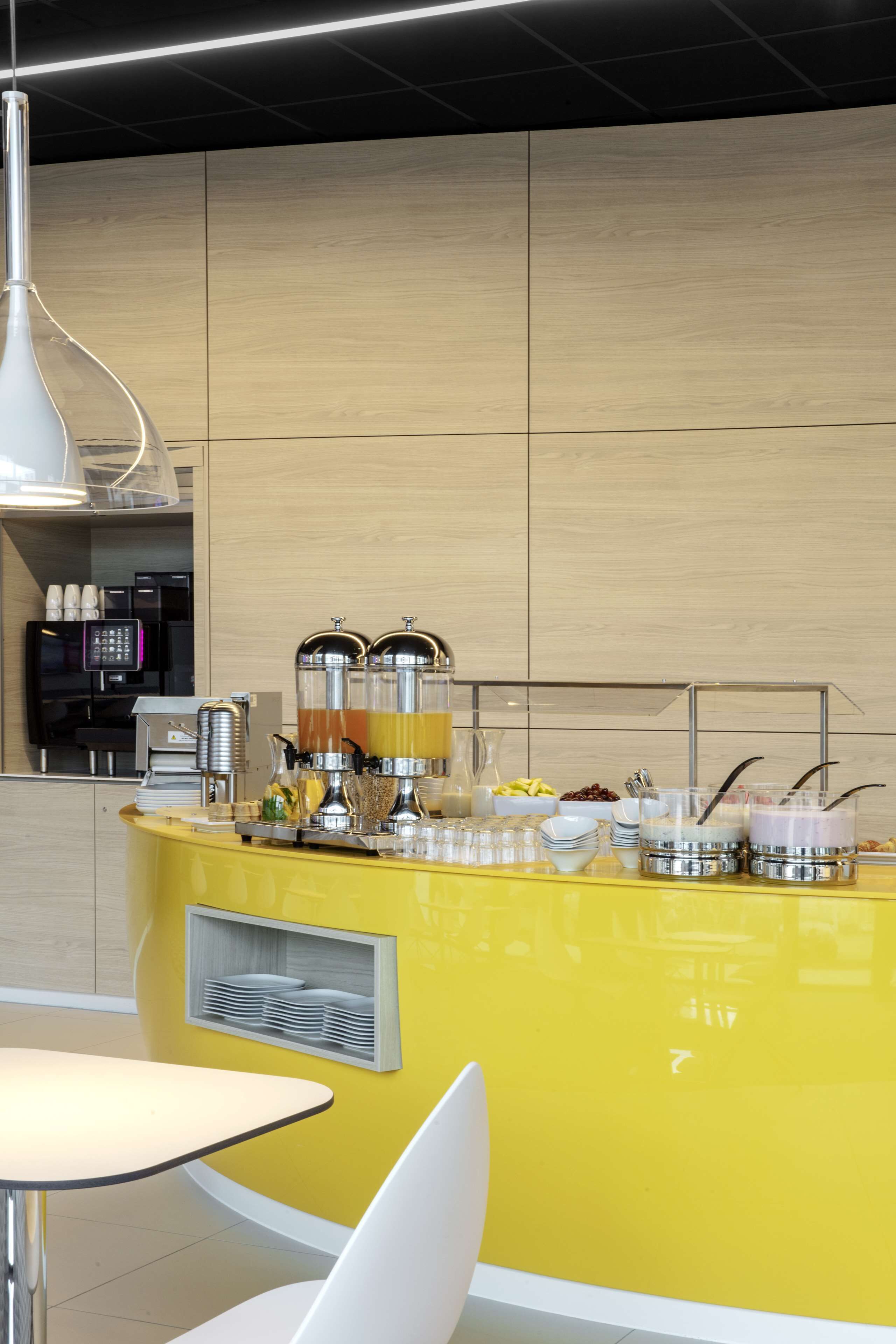 Un espace cuisine moderne avec un comptoir jaune, des appareils en acier inoxydable et un coin café.