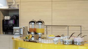 Un espace cuisine moderne avec un comptoir jaune, des appareils en acier inoxydable et un coin café.