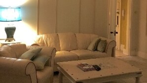 Una sala de estar con un sofá color beige, un sillón a juego, una mesa de centro y una araña.