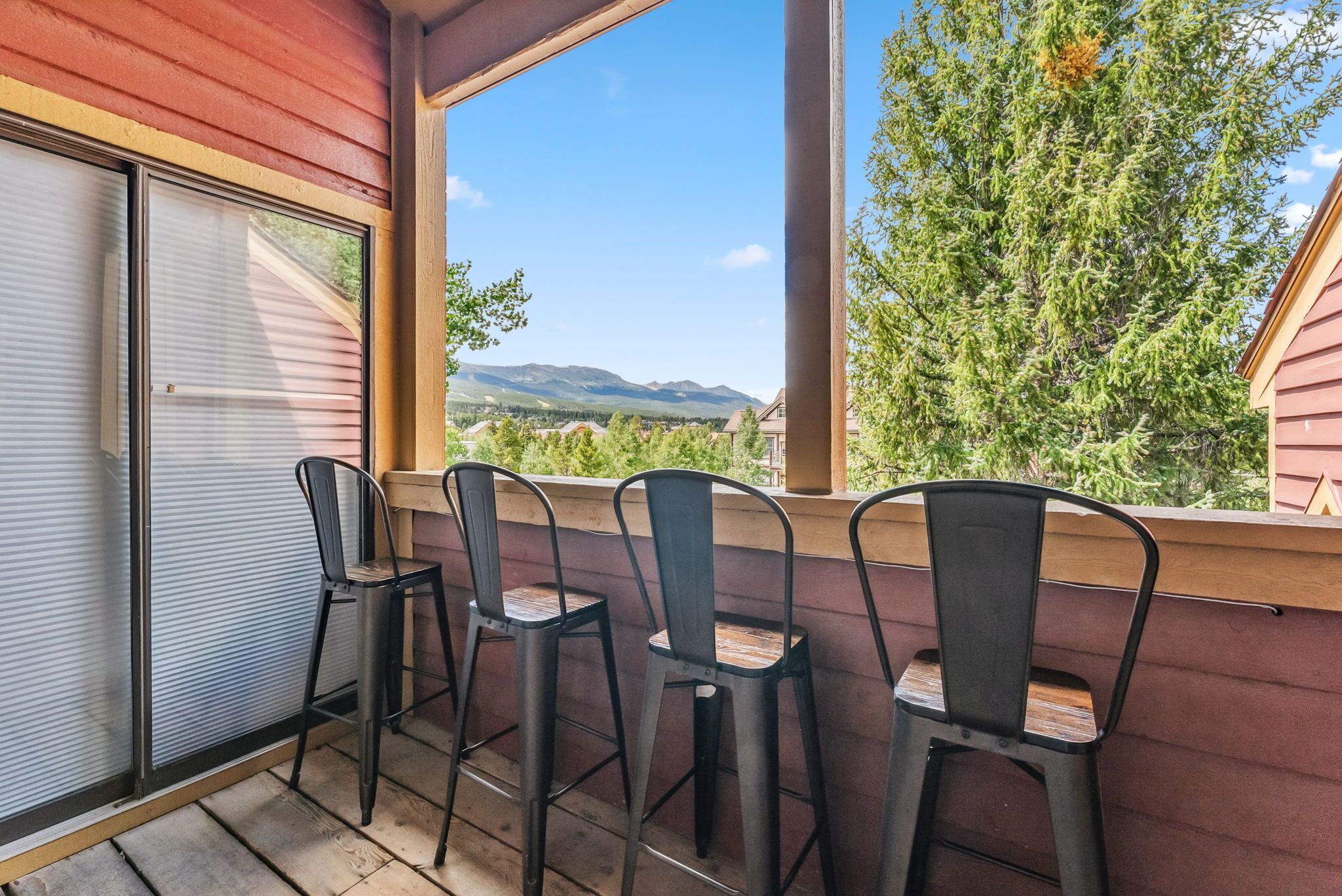 A balcony with three metal chairs and a sliding glass door.