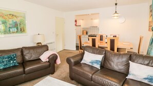 A living room with two brown leather sofas, a white coffee table, and a kitchen in the background. - Brunston Castle (Girvan)