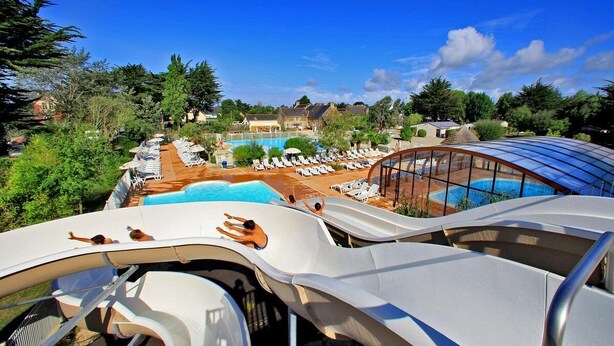 A water park with multiple slides, a swimming pool, and lounge areas with sunbeds.