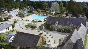 A courtyard with a swimming pool, stone buildings, and a small garden area.