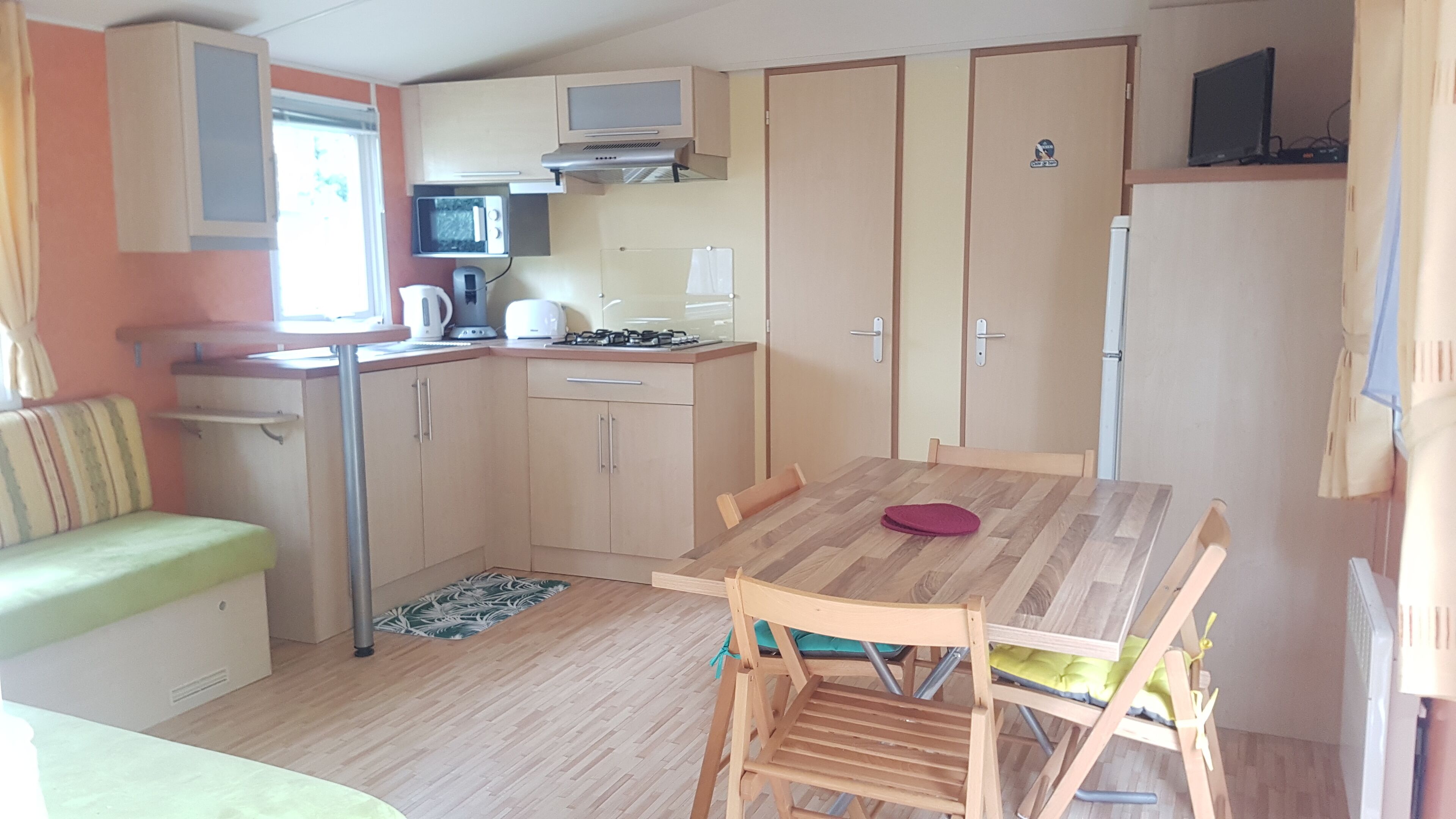 A compact kitchen with a dining area, including a table and chairs, a microwave, a kettle, and a stove.