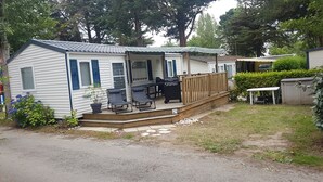 A mobile home with a porch, outdoor seating, and a grill.