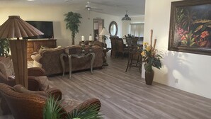 A spacious living room with a large sofa, a television, and a dining area with chairs and a table. - Come and enjoy NAPLES Florida a slice of paradise (Naples)