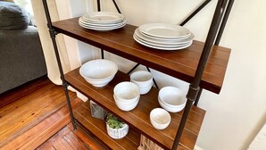 Una estantería metálica con varios cuencos y platos blancos.