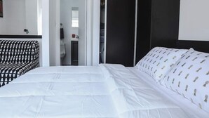 A bedroom with a bed, a wardrobe, and a bathroom.