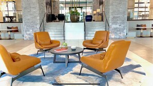 A lobby with a stone wall, a staircase, and a seating area with leather chairs and a coffee table.