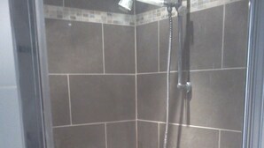 A glass-enclosed shower with a handheld showerhead and a wall-mounted faucet. - Gorges de L'ardèche (Labeaume)