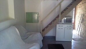 A room with a bed, a small kitchenette, a staircase, and a stone wall. - Gorges de L'ardèche (Labeaume)