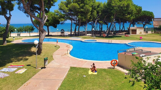 Un espace piscine comprenant deux piscines, une bouée de sauvetage et une plage en arrière-plan.