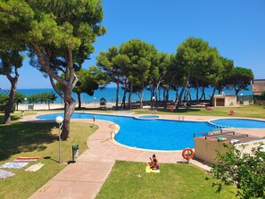 Un espace piscine comprenant deux piscines, une bouée de sauvetage et une plage en arrière-plan.