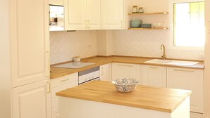 Une cuisine avec des meubles blancs, des plans de travail en bois et un îlot central.