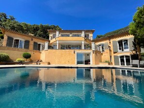 Ein großes, zweistöckiges Haus mit Schwimmbecken davor.