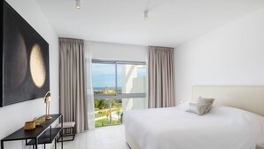 Une chambre d’hôtel moderne avec un grand lit, un bureau et une vue sur l’océan.