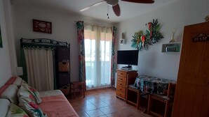 Ein Zimmer mit einem Bett, einem Schreibtisch, einem Deckenventilator, einem Fernseher und einem Kleiderschrank.