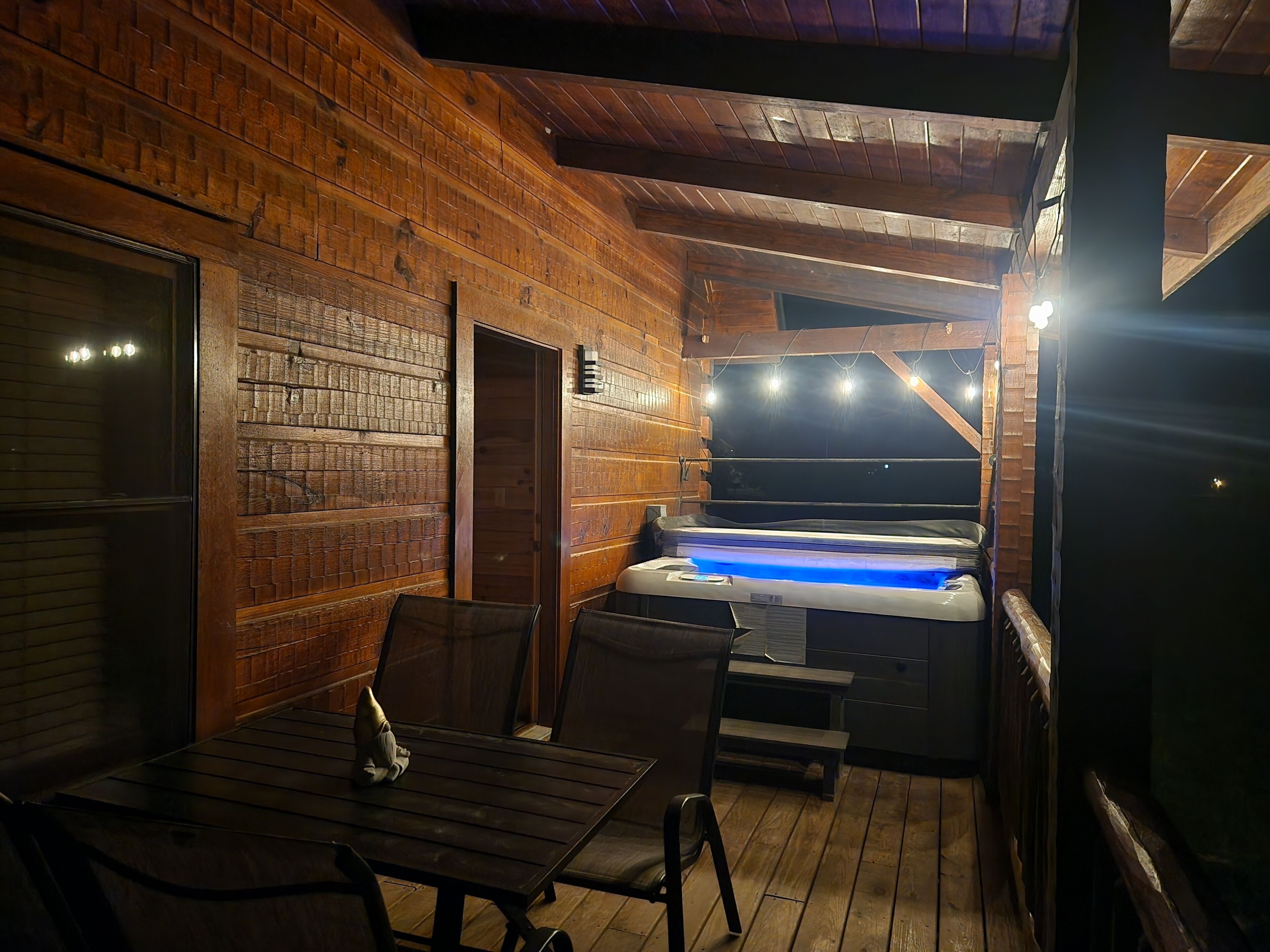 Un intérieur en bois avec un jacuzzi, une table et des chaises.