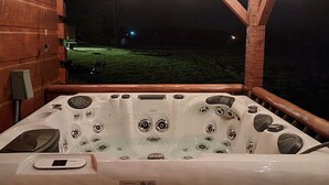A hot tub with a control panel and a view of a grassy area at night. - Tranquility at Fall Creek Falls (Spencer)