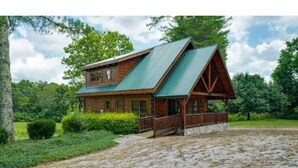 A two-story log cabin with a green metal roof and a porch. - Tranquility at Fall Creek Falls (Spencer)