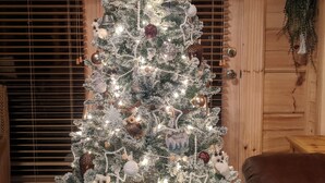A Christmas tree with lights and ornaments in a room with wooden walls and a window with blinds. - Tranquility at Fall Creek Falls (Spencer)