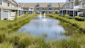 A residential building with a central water feature and a lawn. - Rehoboth/Lewes Townhouse Pond View, Community Pool, Golf & 10-Min Drive to Beach (Rehoboth Beach)