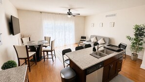 A modern kitchen with a dishwasher, a dining area with a table and chairs, a sofa, and a ceiling fan. - Rehoboth/Lewes Townhouse Pond View, Community Pool, Golf & 10-Min Drive to Beach (Rehoboth Beach)
