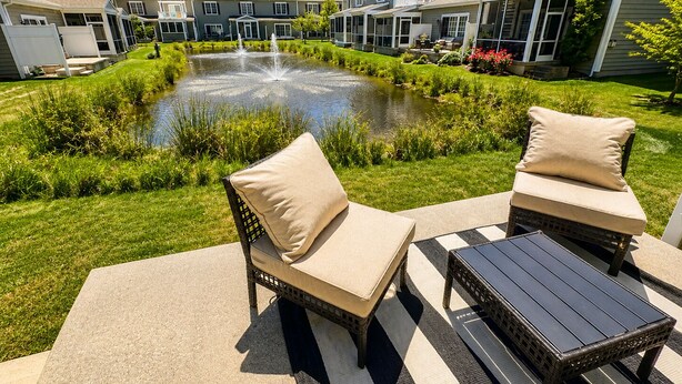 A courtyard with a fountain, two wicker chairs with cushions, and a small table. - Rehoboth/Lewes Townhouse Pond View, Community Pool, Golf & 10-Min Drive to Beach (Rehoboth Beach)