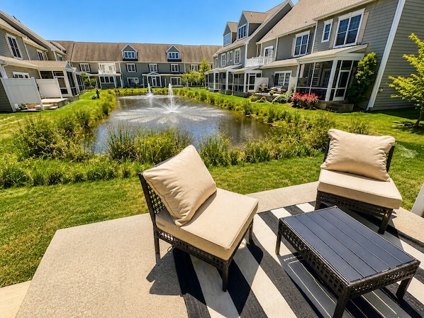 A courtyard with a fountain, two wicker chairs with cushions, and a small table.