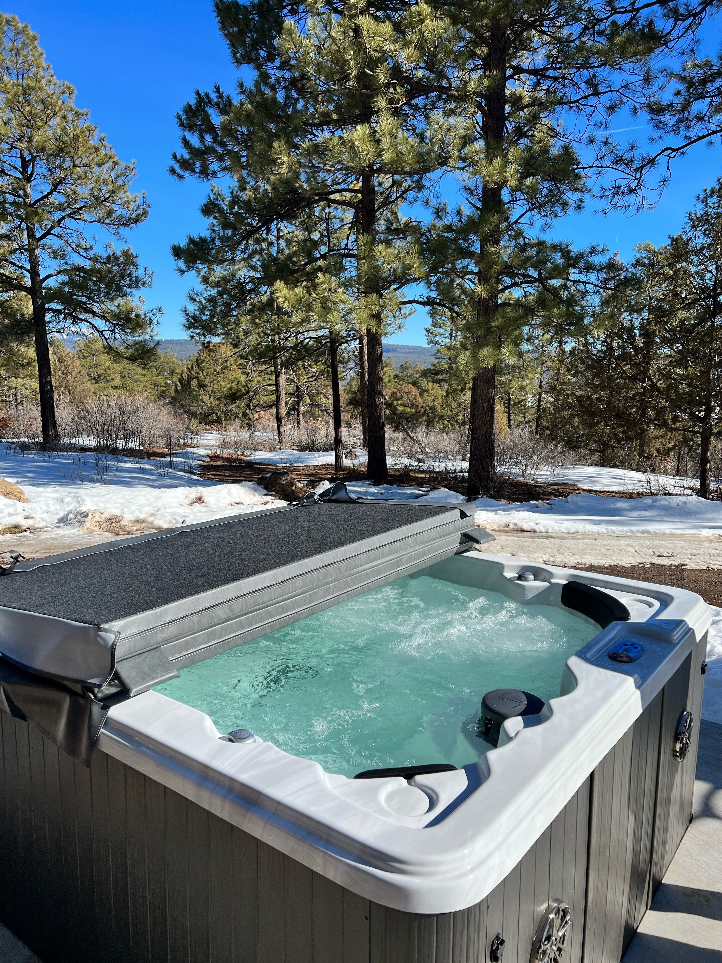 A hot tub in a forested area with snow on the ground.