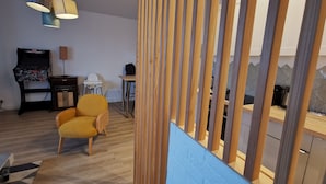 A modern living room with a wooden floor, a yellow armchair, a small table, and a TV stand. - HAPPY KOOL | city center | wifi | private parking (Blois)