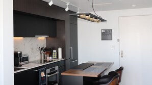 Une cuisine moderne avec des meubles de couleur sombre, un pare-feu en marbre, un four encastré et une machine à café.