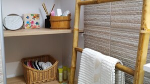 Un baño con estantes de madera, un perchero de bambú y una cesta de mimbre.
