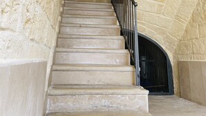 Una escalera de piedra con barandilla de metal que conduce a una puerta.
