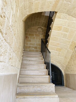 Stairs lead to an upper level, flanked by walls with a textured finish and a metal railing.