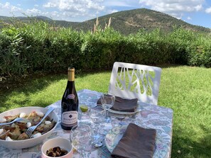 A table set outdoors with a bottle of wine, plates of food, and a white chair. - SEA VIEW and POOL - Beautiful Apartment overlooking the Gulf of St Tropez (Roquebrune-sur-Argens)