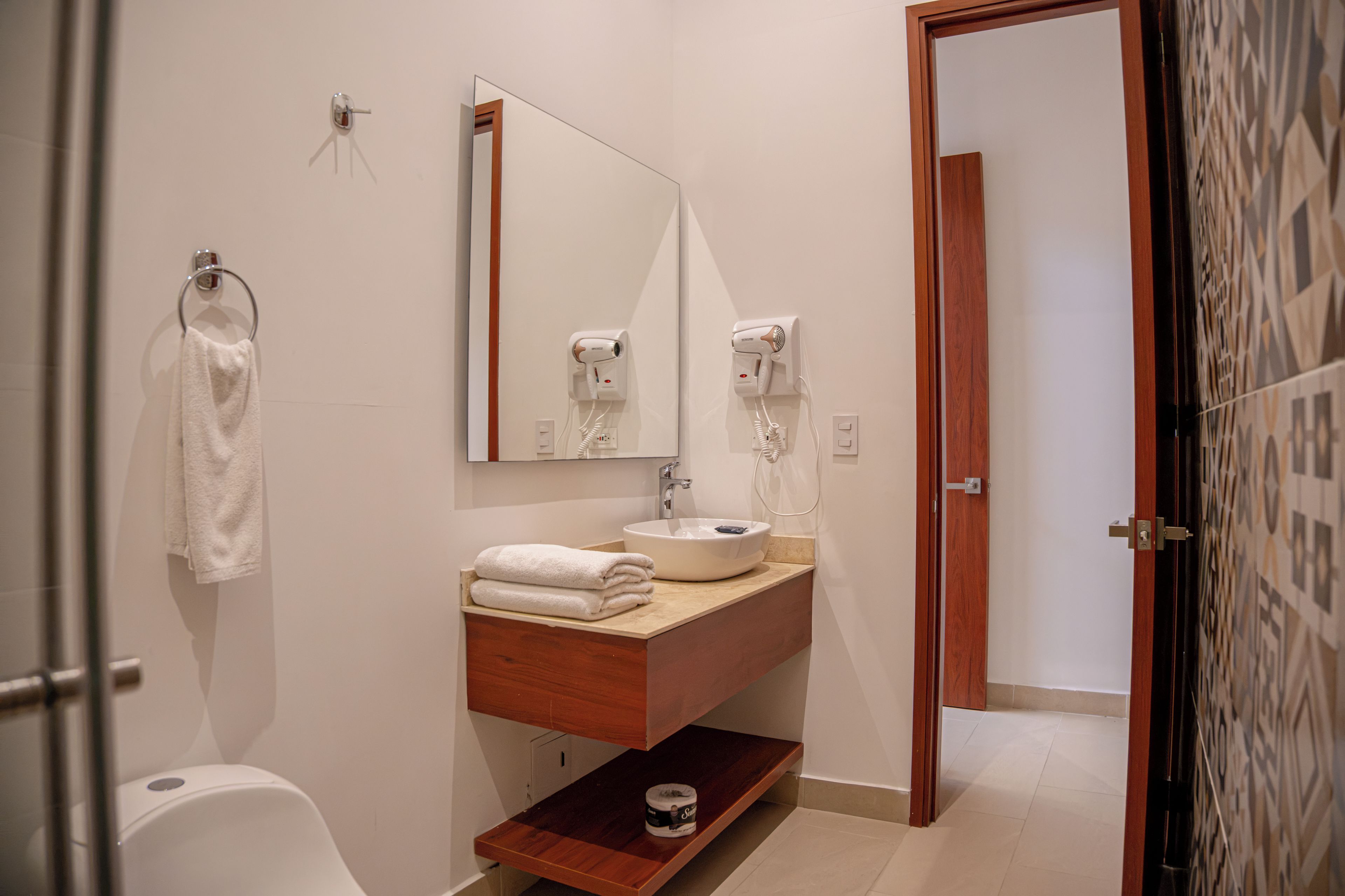 A modern bathroom with a sink, mirror, towel rack, and hairdryer.