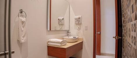 A modern bathroom with a sink, mirror, towel rack, and hairdryer.
